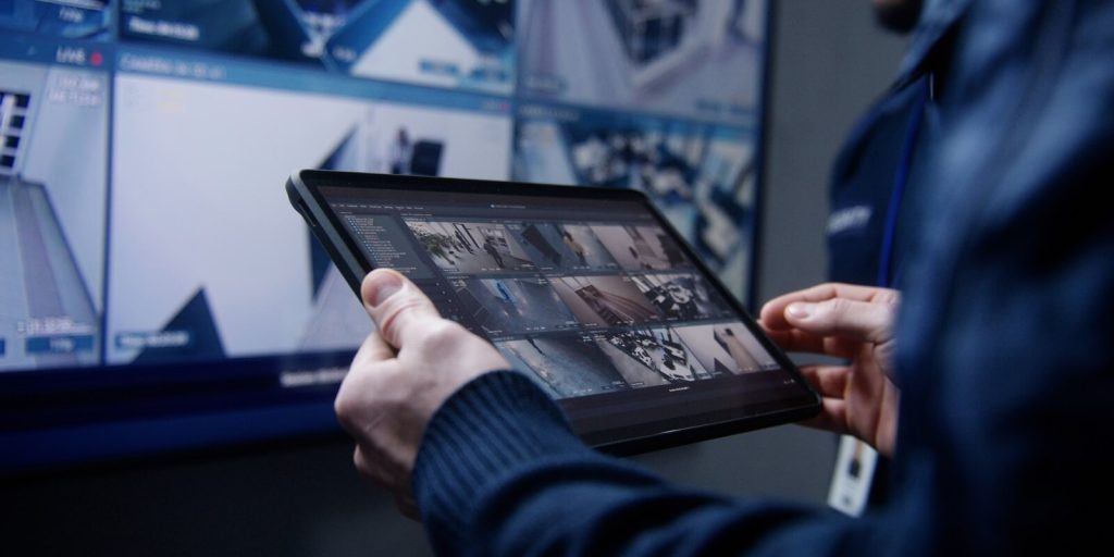 shot of security operator zooming and monitoring cctv cameras using tablet in police surveillance center