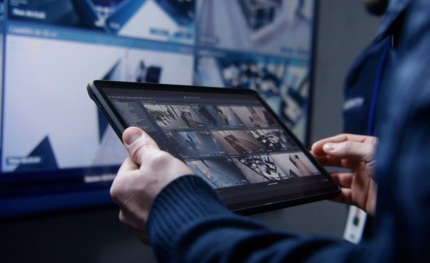 shot of security operator zooming and monitoring cctv cameras using tablet in police surveillance center